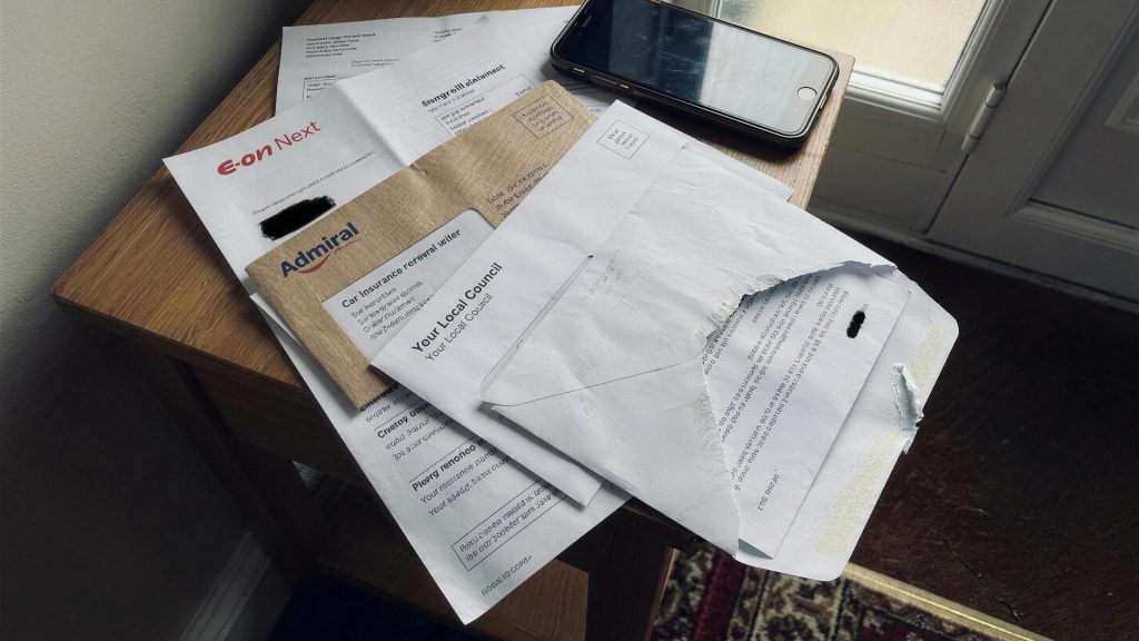 Energy, car insurance and council tax post piled on a hallway table with a phone on top, illustrating cashback on bills